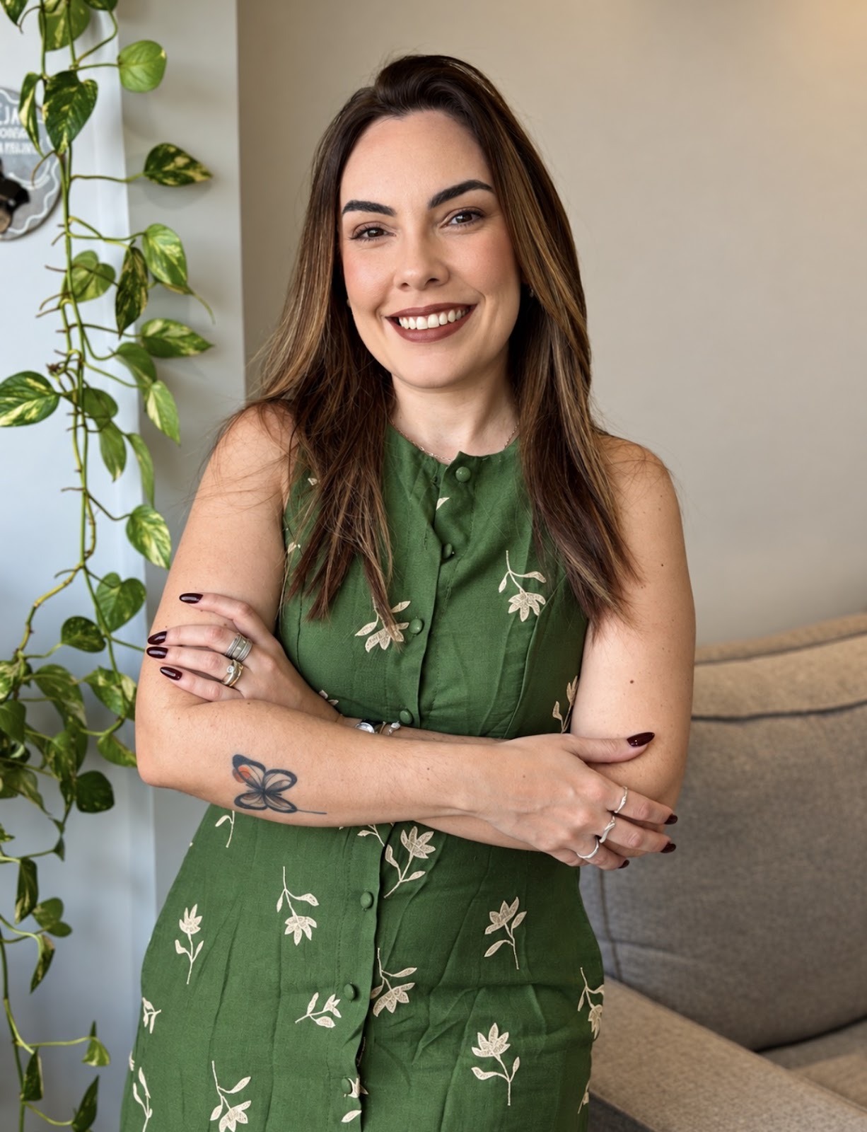 Gabriela Melo sorrindo, de vestido verde junto às plantas, fundadora da Gabi Melo Joias e Acessórios
